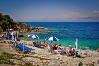 People relaxing at beach against sky