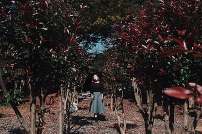 Portrait of young woman standing by tree