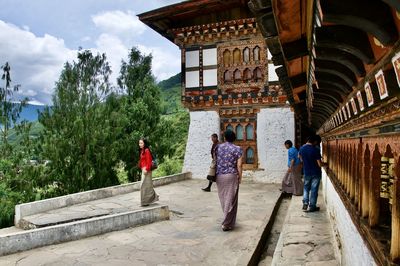 People walking in historic building against sky