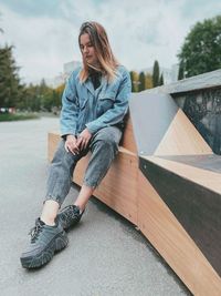 Full length of young woman sitting on seat