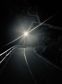 Illuminated road against sky at night