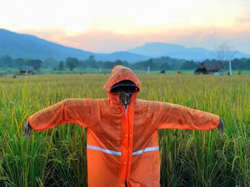 Man standing on field against sky during sunset