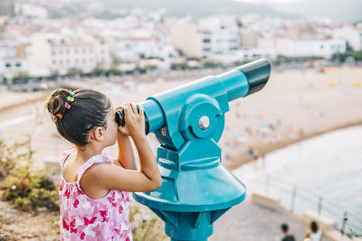 Rear view of girl holding umbrella against city in background