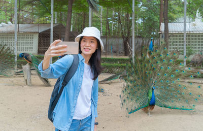 Smiling woman recording video against peacock