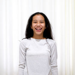 Portrait of smiling girl standing against curtain