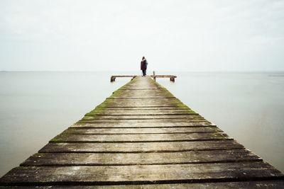 Rear view of pier over sea against sky