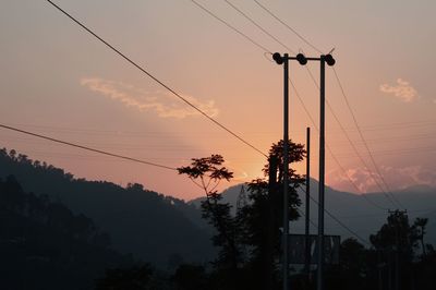 Low angle view of silhouette electricity pylon against sky during sunset