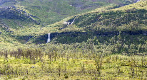 Scenic view of green landscape with waterfall