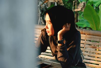 Woman in hijab looking away against plants