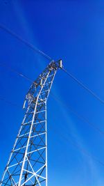 Low angle view of electricity pylon against blue sky