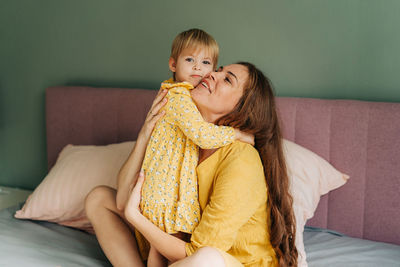 Portrait of cute girl sitting on bed at home