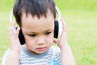 Close-up of cute boy wearing headphones at park
