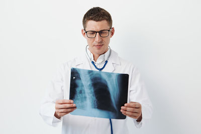 Portrait of doctor standing against white background