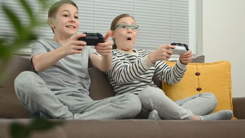 Smiling sibling playing video game at home