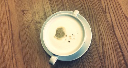 Directly above shot of coffee cup on wooden table