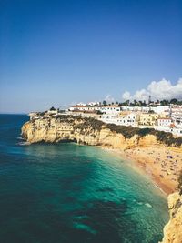 Scenic view of sea and buildings against blue sky