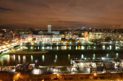 Illuminated bridge over river against sky at night