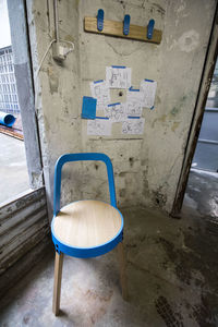Empty chairs and table against wall in abandoned building