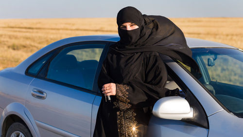 Midsection of woman standing in car