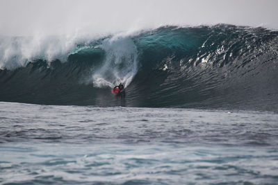 Man surfing in sea against sky