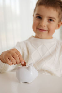 Little boy putting money coin into piggy bank for saving money. wealth, budget, investment, finance