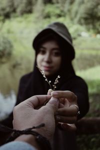 Cropped hand giving flower to woman