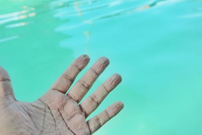 Cropped hand over swimming pool