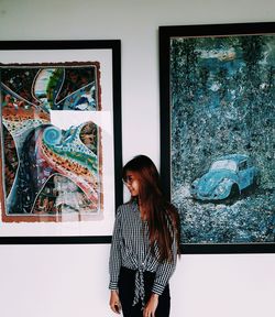 Portrait of young woman standing against wall