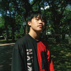 Portrait of young man standing against trees