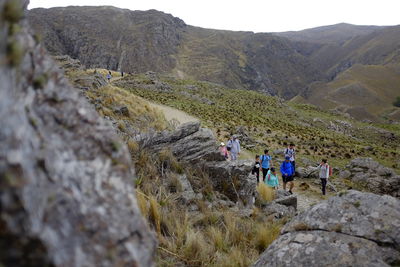 People on rocks against mountains