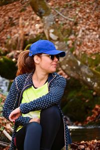 Young woman looking away while sitting outdoors