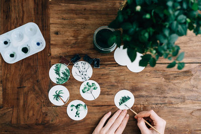 Cropped hands of woman doing aquarelle at wooden table