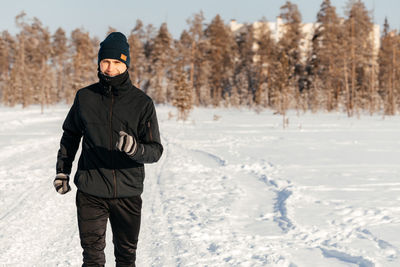 Full length of a happy middle-aged athlete running in nature on a snowy winter day. outdoor fitness