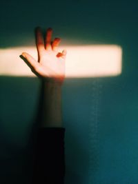 Close-up of human hand against sunlight on wall