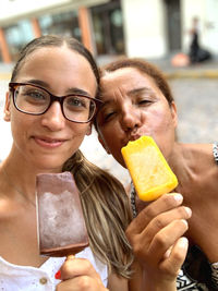 Portrait of smiling women with ice cream on street