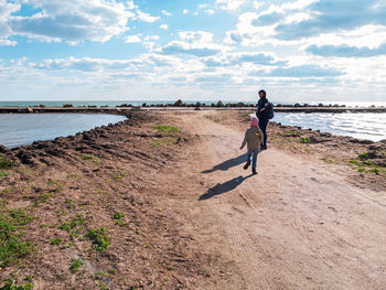 Father daughter smiling walking on empty beach. lifestyle real people happy active family having fun