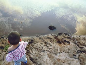 Rear view of boy on rock by sea