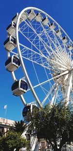 Low angle view of ferris wheel against blue sky