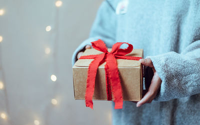 Close-up of person holding red wrapped in box