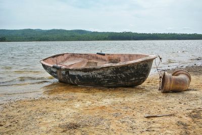 Abandoned boat on shore against sky