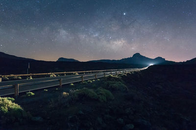 Scenic view of bridge over mountains against sky at night