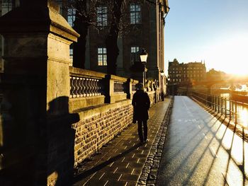 Rear view of man walking on bridge in city