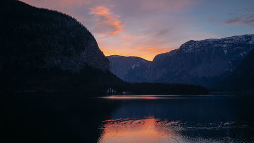 Scenic view of lake by mountains against sky during sunset