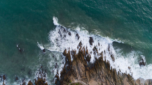 Aerial view of waves splashing on rock 