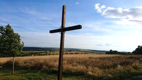 Cross on field against sky