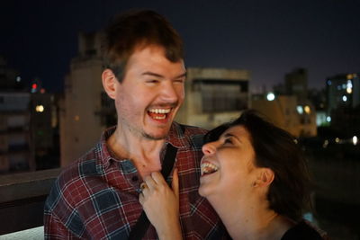 Close-up of couple laughing in city at night