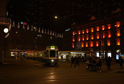 People on illuminated road at night