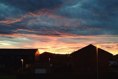 Silhouette houses against sky during sunset