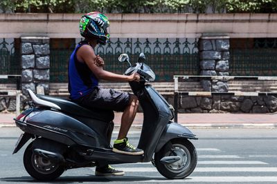 Man riding motor scooter on road