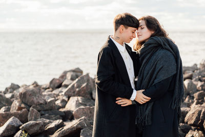 Friends standing on rock by sea